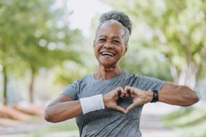 An older adult holding her hands in the shape of a heart